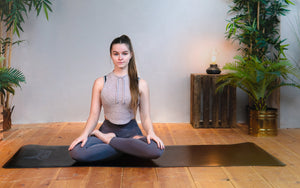 junge frau in yoga pose auf nachhaltiger und ökologischer yogamatte in schwarz mit hoher rutschfestigkeit
